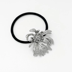 Close-up of elegant silver flower metal ornament on a premium black elastic hair tie