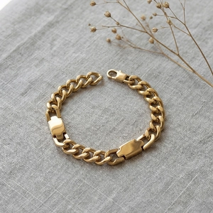 Gold U-link Cuban chain bracelet on linen background with elegant dried flower decor