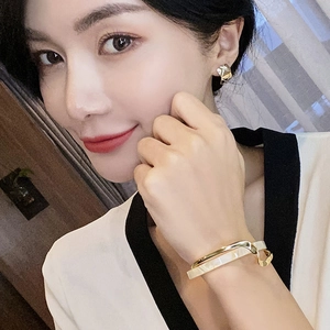 Close-up of gold plated layered bracelet and matching geometric stud earrings on a model
