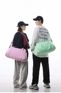 Models carrying large capacity pink and green sports duffel bags for gym and travel use