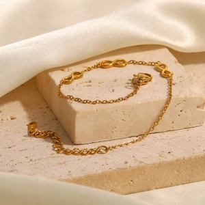 Detailed shot of infinity symbol bracelet in gold finish with an adjustable clasp chain