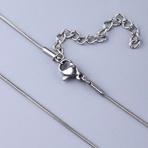 Macro detail of silver stainless steel round snake chain with lobster clasp and extender