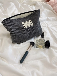 Detailed view of herringbone fabric makeup bag with Pleasant Time woven label and top zipper