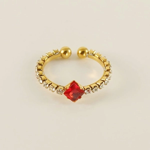 Macro detail of gold adjustable ring featuring red rhombus gem and circular zircon accents