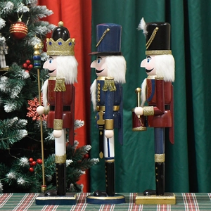 Three wooden Christmas nutcracker king figures with red bodies on festive background