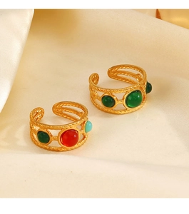 Detail of 18K gold-plated rings with green and red resin stones on beige silk
