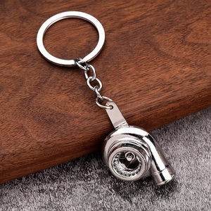 Detail of polished silver zinc alloy turbocharger model keychain on wood surface