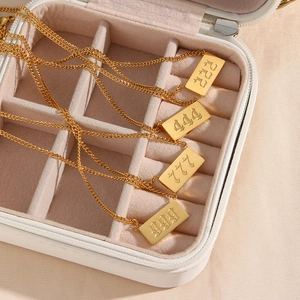 Primer plano de collares con colgante de número angelical dorado en un joyero blanco.