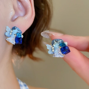 Macro detail of butterfly crystal stud earrings with blue stones and pearls for women