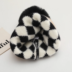 Winter knitted baby beanie with black and white checkerboard pattern and plush pompom