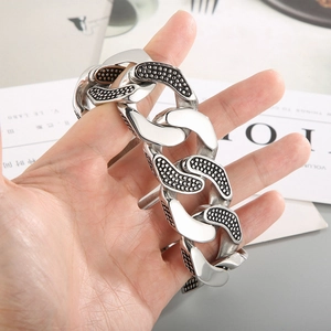 Primo piano del bracciale largo in acciaio inossidabile con pois neri in mano