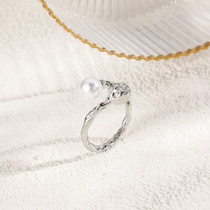 Macro detail of silver ring with irregular lava texture and a lustrous round white pearl