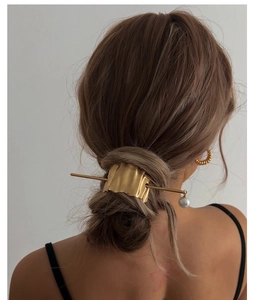 Detailed back view of a woman wearing a gold irregular hair pin with a pearl pendant
