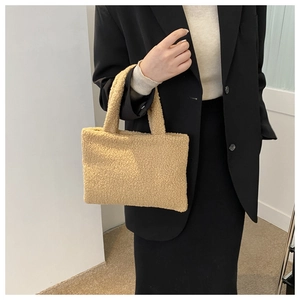 Detail of soft beige plush handbag held by model showing texture and minimalist design