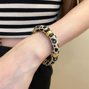 Detail of acrylic leopard print bracelet with polished gold metal spacers on wrist