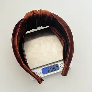 Brown velvet knotted headband weighing approximately 60.97 grams on a digital scale