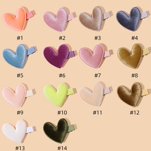 Detail showing 14 different colors of heart-shaped velvet hair clips for kids