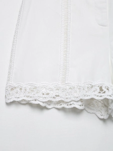 Gros plan sur l'ourlet en dentelle crochetée et broderie ajourée du chemisier d'été