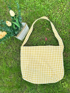 Yellow plaid canvas tote bag for women shown on a green lawn with spring flowers