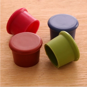 Close-up of four colorful food-grade silicone bottle caps on a natural wooden background