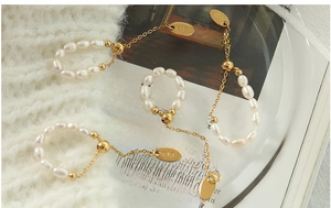 Détails macro de bagues en perles d'eau douce et or 18 carats sur un pull en maille blanche