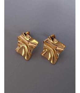 Dettaglio macro di orecchini d'oro irregolari con finitura lucida in oro 18K