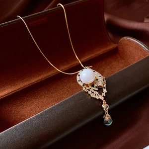 Detail of gold leopard pendant with sparkling zircon, white pearl, and black pearl drop