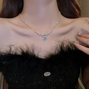 Detailed close-up of water drop necklace with faux pearls and blue zircon on model