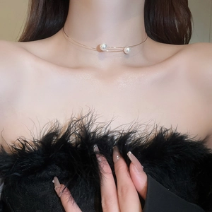 Chic open choker necklace with white pearls on a model wearing a black feathered top