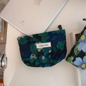 Detail of dark green floral fabric pouch with simple wish label and black zipper closure