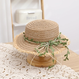 Dettaglio cappello in rafia a cima piatta con decoro a vite e finitura con frange