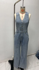 Vue détaillée d'une combinaison en jean bleu clair avec col en V et boutonnage à l'avant