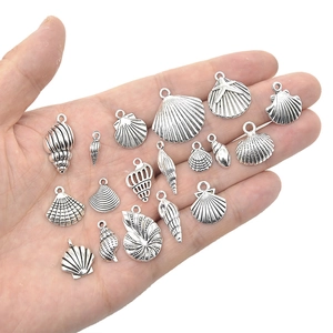 Collection of silver seashell and starfish alloy charms for DIY jewelry making on a palm