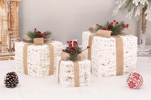 Close-up of three white string Christmas gift boxes with pine cones and burlap bows