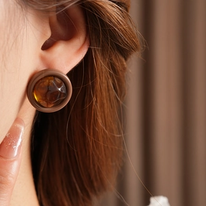 Close-up of a retro amber resin round stud earring on a model for a chic daily look