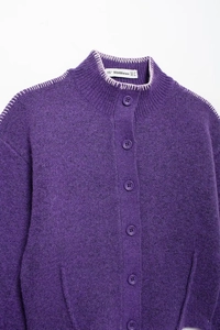 Dettaglio del cardigan in maglia viola con cuciture rosa a contrasto e bottoni