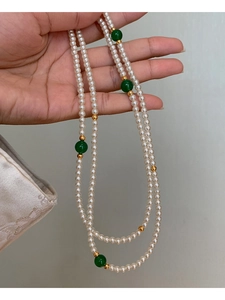 Detail of multi-layer faux pearl necklace with green jade beads and golden accents