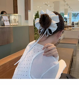 Detail view of a white satin scrunchie with long ribbons on a ponytail hairstyle