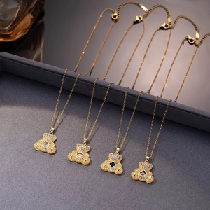 Four elegant bear necklaces with four-leaf clover zircon pendants on a gray display tray