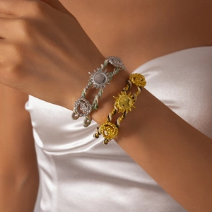 Detail of woven sun and rose charm bracelets on a model showing metallic textures