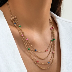Detailed view of layered gold necklace with colorful beads on a model for casual style