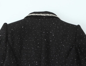 Detail of black tweed jacket featuring silver sequins and elegant braided trim on the collar