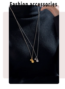 Detail of teardrop pendant necklaces in gold and silver finish on a black sweater