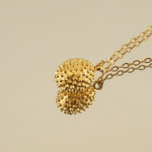 Close-up of 18k gold plated durian-textured sphere pendant necklace with fine chain