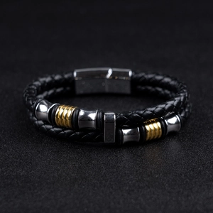 Close-up of black leather braided men's bracelet with silver and gold magnetic clasp