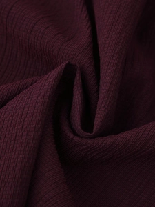 Detail of burgundy linen fabric showing vertical stripe texture and natural pleated wrinkles