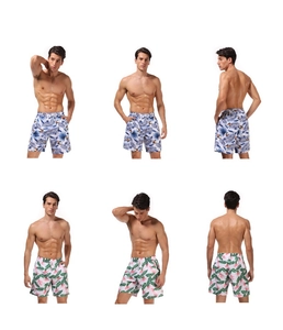 Detail view of men's beach shorts showing tropical coconut tree and floral prints