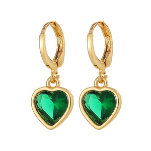 Détail de boucles d'oreilles cœur dorées avec des pierres précieuses en cristal vert