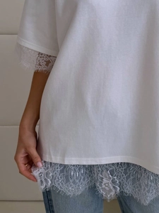 Close-up of intricate lace trim detail on the sleeve and hem of white cotton t-shirt