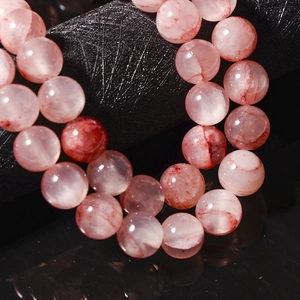 Macro shot of pink Persian jade round beads showing natural texture on black leather
